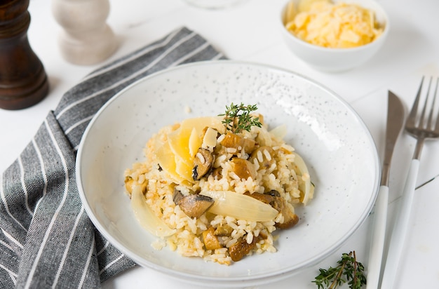 Risotto con funghi porcini e parmigiano su sfondo chiaro, fuoco selettivo