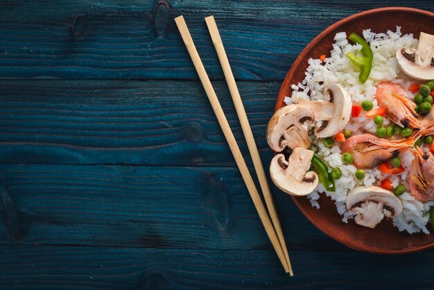 Risotto con gamberi e verdure Frutti di mare Cucina asiatica Su uno sfondo di struttura in legno Vista dall'alto Spazio libero