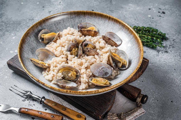 Risotto italiano alle vongole in un piatto rustico con erbe aromatiche Backgroud grigio Vista dall'alto