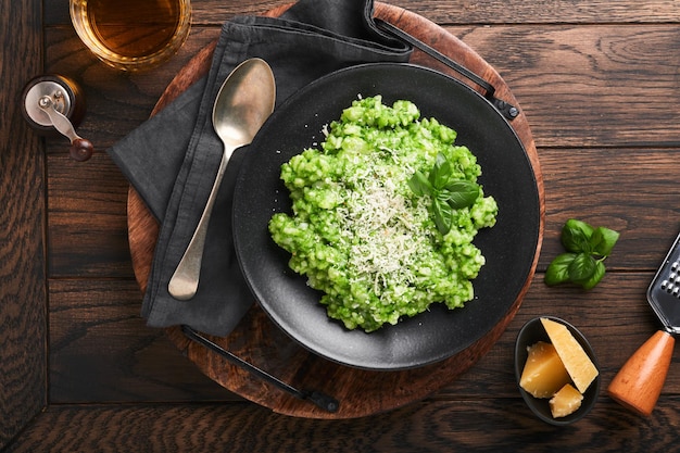 Risotto italiano Delizioso risotto con salsa di pesto o pesto di aglio selvatico parmigiano di basilico e bicchiere di vino bianco su sfondo vecchio tavolo in legno Cena italiana Vista dall'alto con spazio per la copia