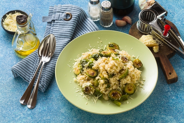 Risotto italiano di primavera con cavoletti di Bruxelles e parmigiano sul tavolo.