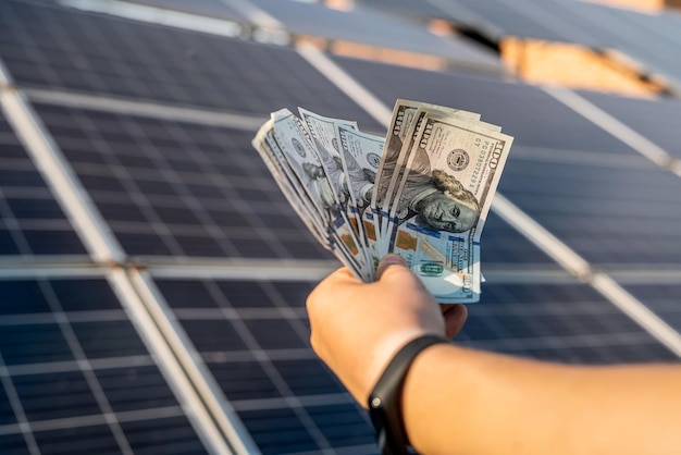 Risparmio di denaro con l'energia solare e pannelli solari Mano con dollari