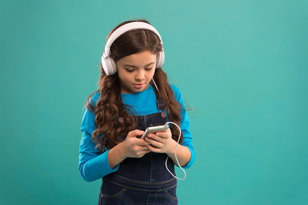 Rispondi all'e-mail bambino piccolo crea playlist su smartphone bambina usa lettore mp3 studio nella vita moderna ragazza usa dispositivo digitale moda casual per bambini bambino capelli lunghi ascolta musica in cuffia