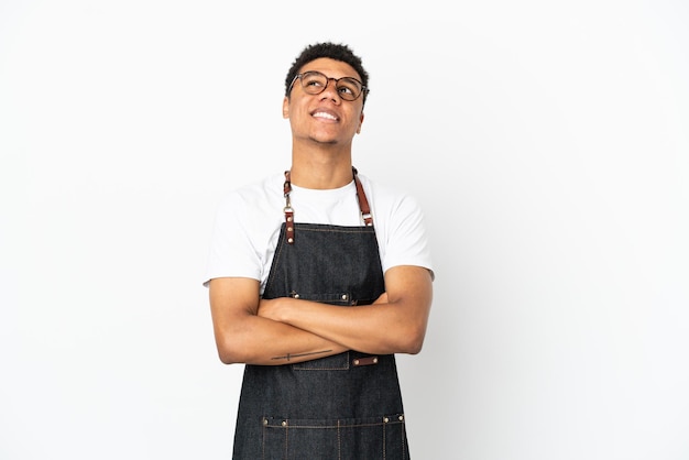 Ristorante cameriere afroamericano uomo isolato su sfondo bianco alzando lo sguardo mentre sorride