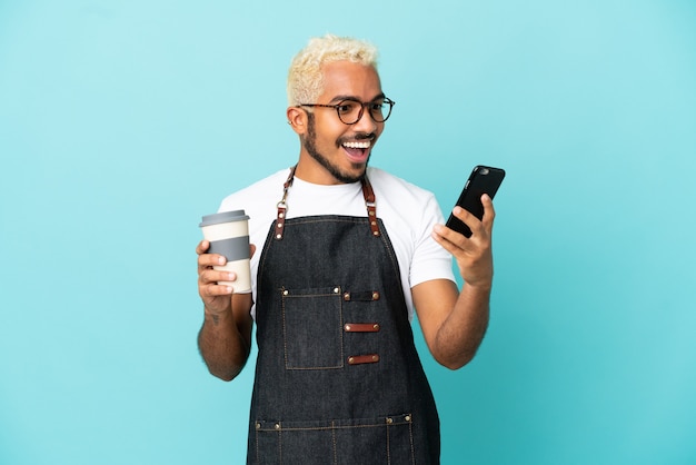 Ristorante cameriere colombiano uomo isolato su sfondo blu tenendo il caffè da asporto e un mobile