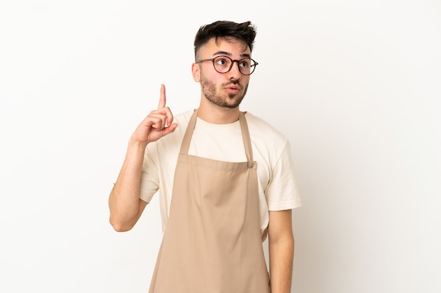 Ristorante cameriere uomo caucasico isolato su sfondo bianco pensando a un'idea che punta il dito verso l'alto