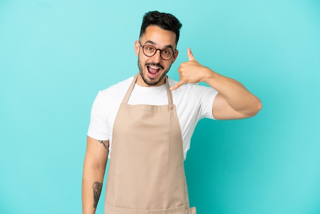 Ristorante cameriere uomo caucasico isolato su sfondo blu che fa il gesto del telefono. Richiamami segno