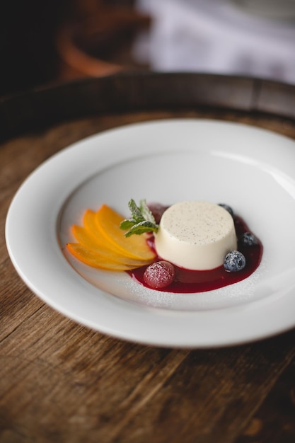 Ristorante che serve dessert. Panna cotta su un piatto bianco con marmellata e frutta fresca