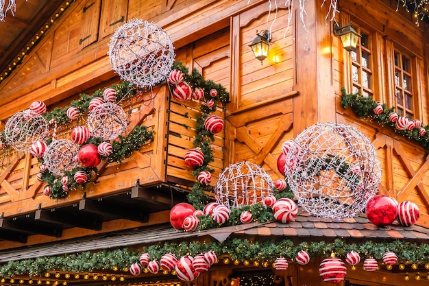 Ristorante in legno retrò edificio decorato di abete artificiale con ghirlanda e molte palle di Natale rosse e bianche al giorno d'inverno, senza neve.