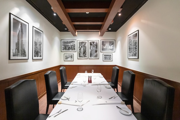 Ristorante interno di steakhouse con mobili di lusso contemporanei in stile newyorkese, eleganti sedie in pelle nera. Cucina raffinata, spaziosa e confortevole