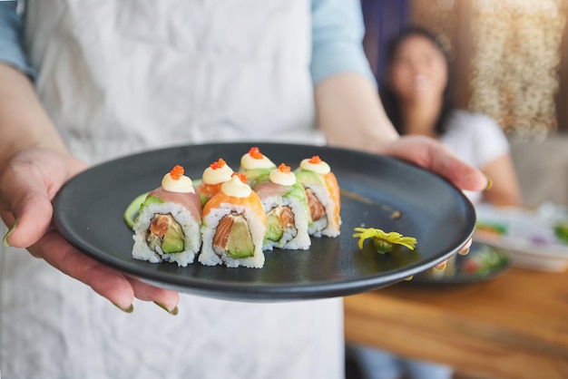 Ristorante mani e primo piano di sushi su un piatto per il lusso sano e autentico cucina asiatica piatto fine dining e zoom di un pasto giapponese per pranzo cena o cena in un caffè tradizionale