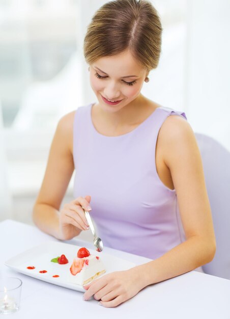 ristorante, persone e concetto di vacanza - giovane donna sorridente che mangia il dessert al ristorante