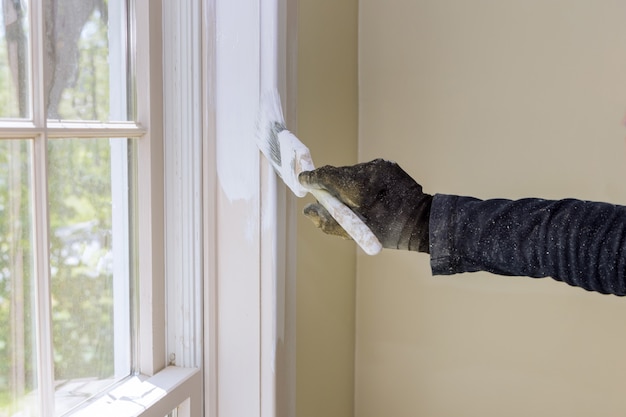 ristrutturazione della casa nel tuttofare dipinge con uno strato di modanatura della finestra del pennello di colore bianco