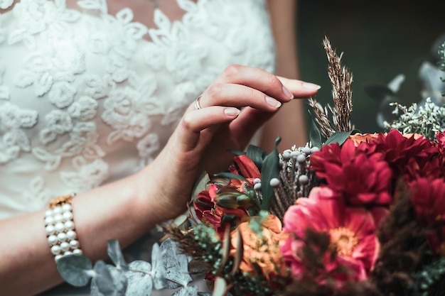 Ritaglia donna sfocata in abito da sposa bianco con bouquet vibrante incredibile e petali commoventi