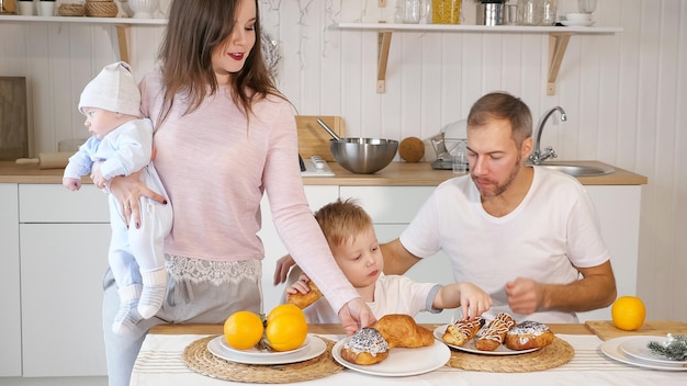 Ritaglia la donna con il bambino che serve panini per marito e figlio mentre fanno colazione insieme