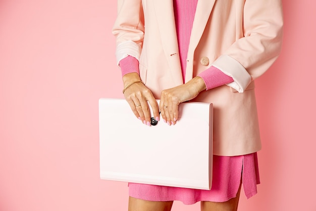 Ritaglia la foto delle mani femminili che tengono la cartella di file per i documenti su sfondo rosa, foto in studio, donna irriconoscibile. Persona d'affari femminile. scartoffie