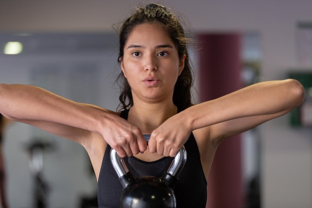 Ritaglia la giovane donna che solleva pesi in palestra