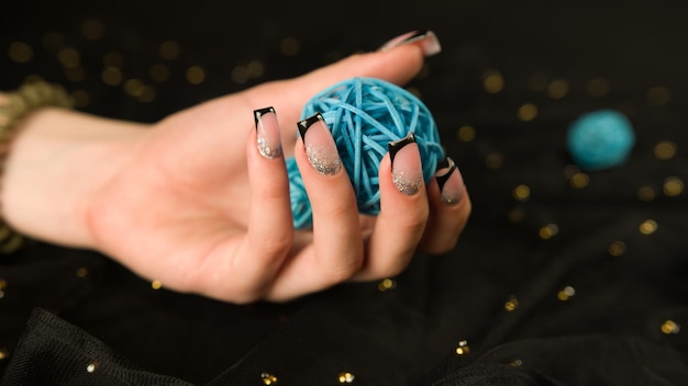 Ritaglia la mano della ragazza con la manicure Femmina irriconoscibile che mostra lo smalto per unghie su sfondo nero