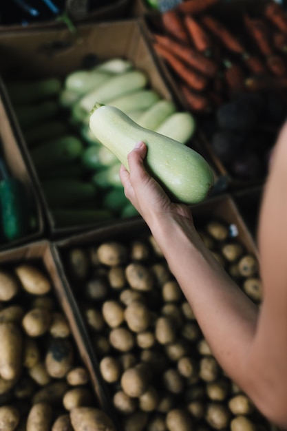 Ritaglia la persona che sceglie le zucchine nel mercato esterno