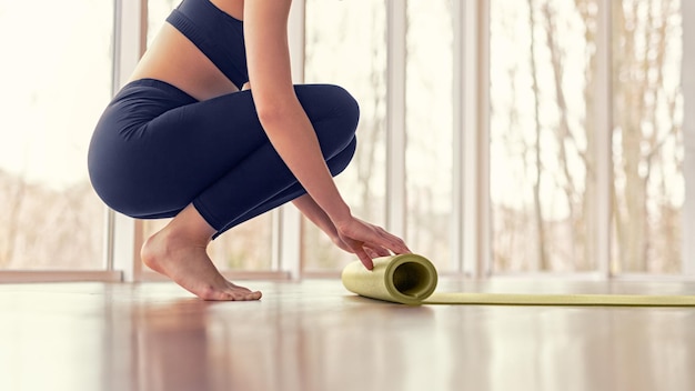 Ritaglia la stuoia di srotolamento femminile prima della lezione di yoga