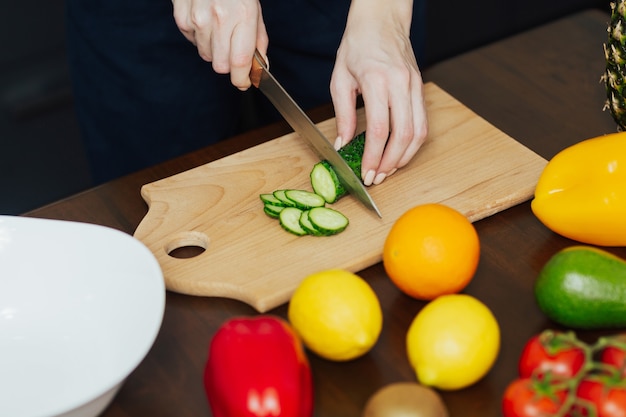 Ritagliata colpo di donna sta preparando insalata di verdure in cucina.