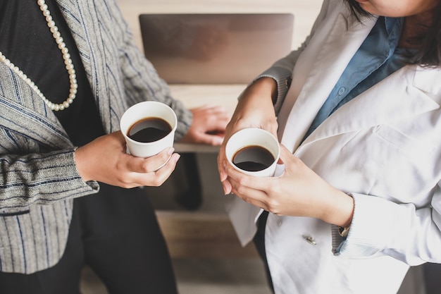 Ritagliata colpo di due donne d'affari hanno un caffè in ufficio