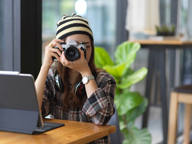 Ritagliata colpo di giovane donna utilizzando una fotocamera mentre si lavora in un ambiente di lavoro confortevole