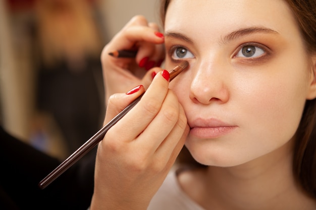 Ritagliata da vicino di una giovane donna bellissima, ottenendo il trucco fatto da truccatore professionista