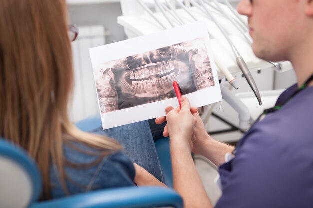 Ritagliato primo piano di un dentista che discute la scansione a raggi X dentale con il suo paziente