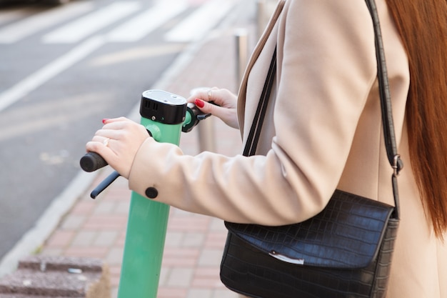 Ritagliato primo piano di una donna che usa uno scooter elettrico per viaggiare in città