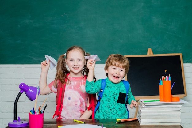 Ritorno a scuola e tempo felice Poco pronto per studiare Simpatico ragazzino in età prescolare con bambina in un'aula Spazio copia lavagna