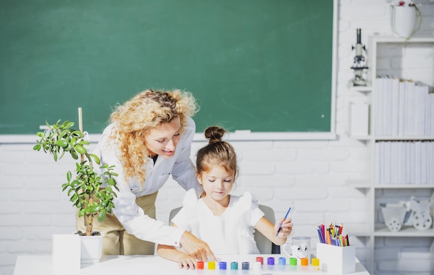 Ritorno a scuola, madre e figlia insieme, l'insegnante di pittura aiuta la bambina