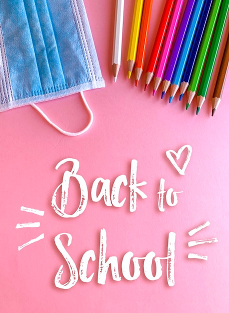 Ritorno a scuola, matite e maschera su sfondo rosa