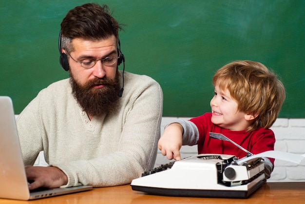 Ritorno a scuola ragazzo che fa i compiti a scuola con il padre insegnante che aiuta i bambini con le loro c...