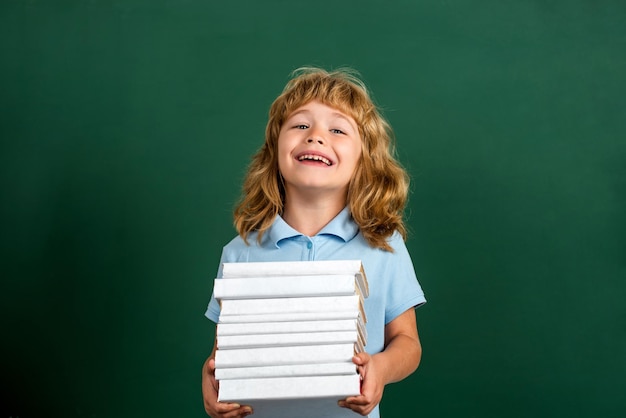 Ritorno a scuola Scolaretto in classe Bambino con una pila di libri con una tavola di malta sulla lavagna