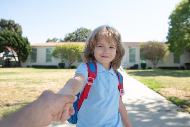 Ritorno a scuola scolaro adorabile che tiene la mano dei padri dei genitori sulla strada per la scuola Concetto di istruzione primaria