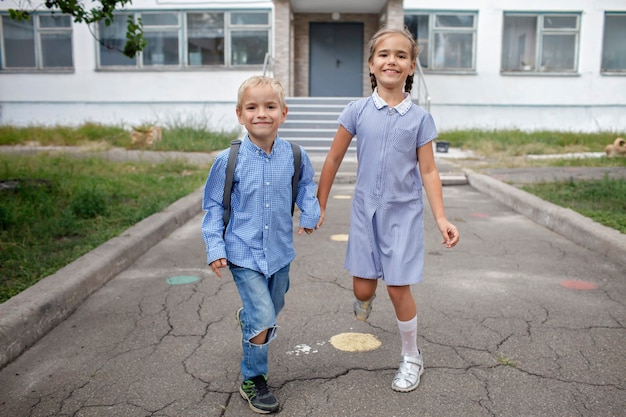 Ritorno ai fratelli di scuola con gli zaini che scappano dalla scuola dopo il loro primo giorno offline