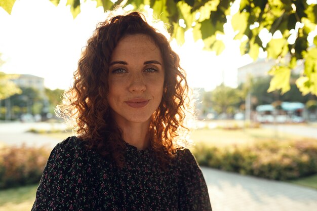 Ritratti di un'affascinante ragazza dai capelli rossi con le lentiggini e un bel viso. La ragazza posa per la telecamera nel centro della città. Ha un ottimo umore e un sorriso dolce