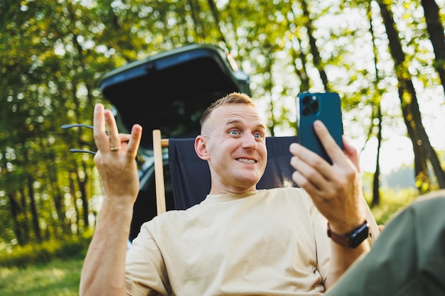 Ritratti di un giovane uomo emotivo che parla al telefono mentre è seduto nel parco Ricreazione in natura lavoro a distanza Fine settimana in natura