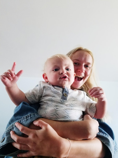 Ritratto a basso angolo di una madre allegra che tiene il figlio contro il soffitto