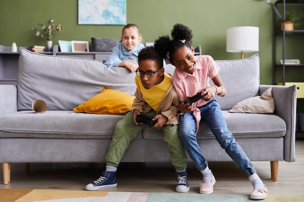 Ritratto a figura intera di fratello e sorella afroamericani che giocano ai videogiochi a casa insieme e combattono
