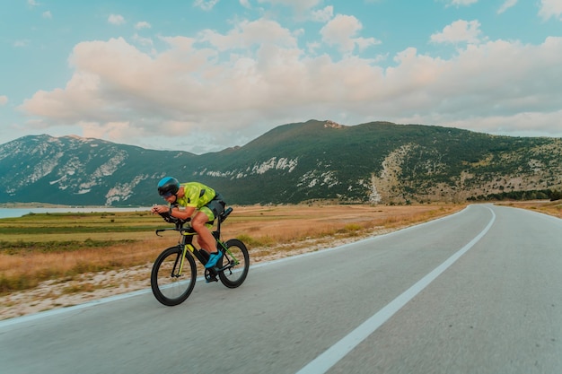 Ritratto a figura intera di un triatleta attivo in abbigliamento sportivo e con un casco protettivo in bicicletta. Messa a fuoco selettiva.