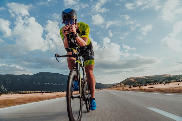 Ritratto a figura intera di un triatleta attivo in abbigliamento sportivo e con un casco protettivo in bicicletta. Messa a fuoco selettiva.