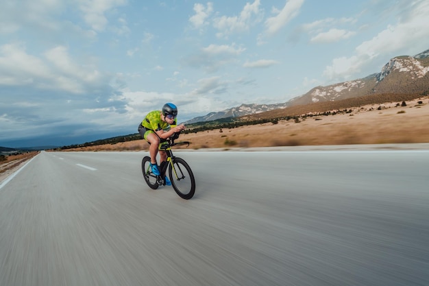 Ritratto a figura intera di un triatleta attivo in abbigliamento sportivo e con un casco protettivo in bicicletta. Messa a fuoco selettiva.