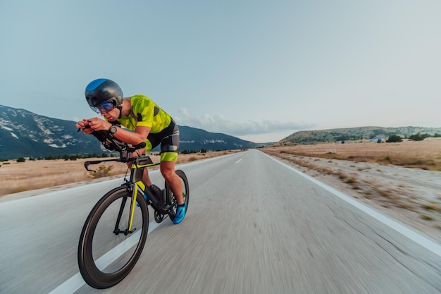 Ritratto a figura intera di un triatleta attivo in abbigliamento sportivo e con un casco protettivo in bicicletta. Messa a fuoco selettiva.