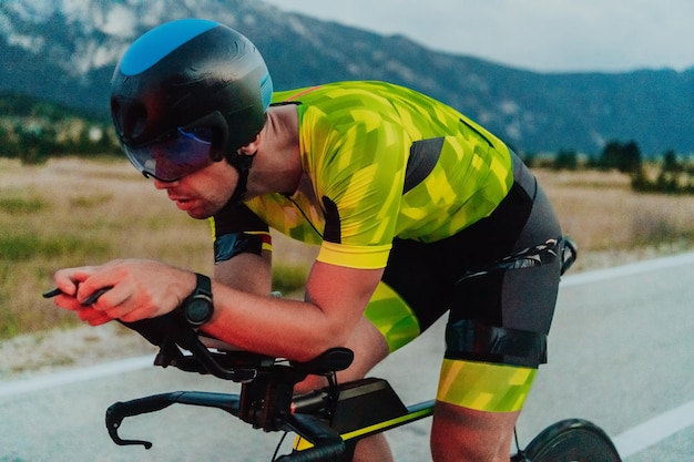 Ritratto a figura intera di un triatleta attivo in abbigliamento sportivo e con un casco protettivo in bicicletta. Messa a fuoco selettiva.