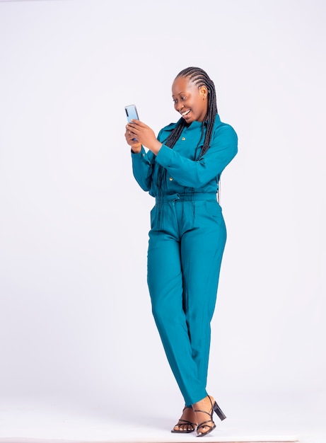 Ritratto a figura intera di una giovane donna d'affari africana nera con un telefono cellulare in piedi eccitato