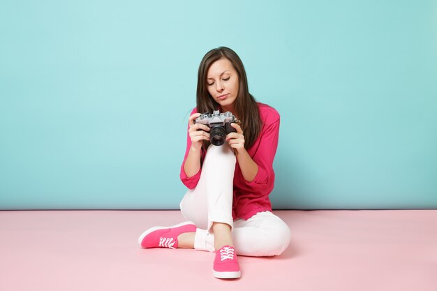Ritratto a figura intera giovane donna in camicia rosa camicetta pantaloni bianchi seduto sul pavimento tenere la fotocamera