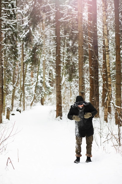 Ritratto all'aperto dell'uomo bello in cappotto e forfora. Uomo barbuto nei boschi invernali.