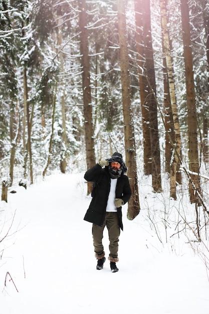 Ritratto all'aperto dell'uomo bello in cappotto e forfora. Uomo barbuto nei boschi invernali.